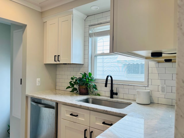 kitchen featuring stainless steel dishwasher, white cabinetry, a sink, and backsplash