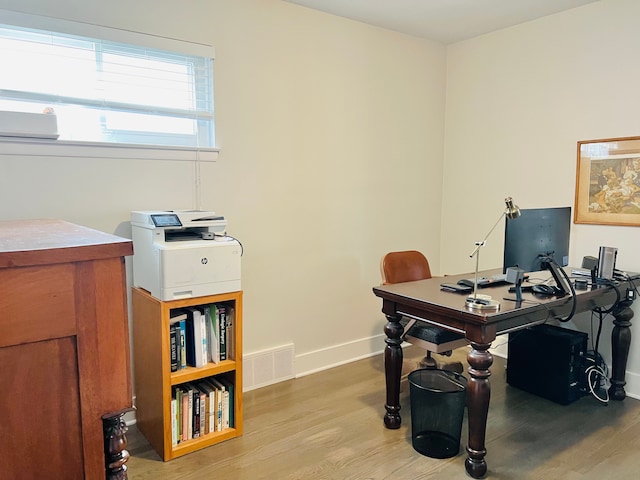 office area featuring baseboards, visible vents, and wood finished floors