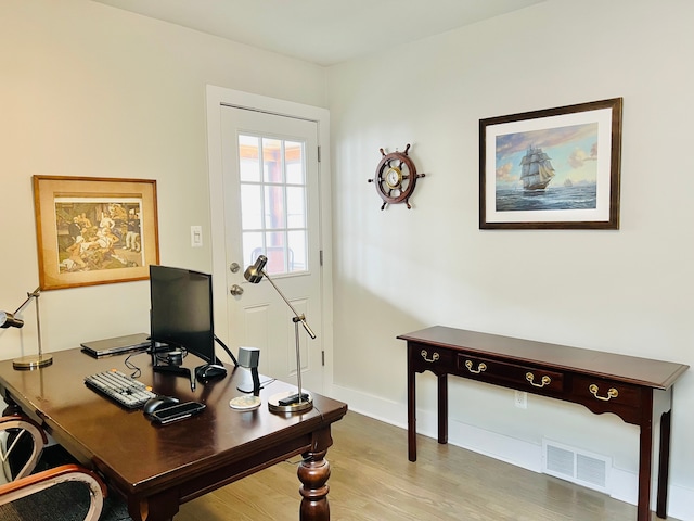 office space with baseboards, visible vents, and wood finished floors