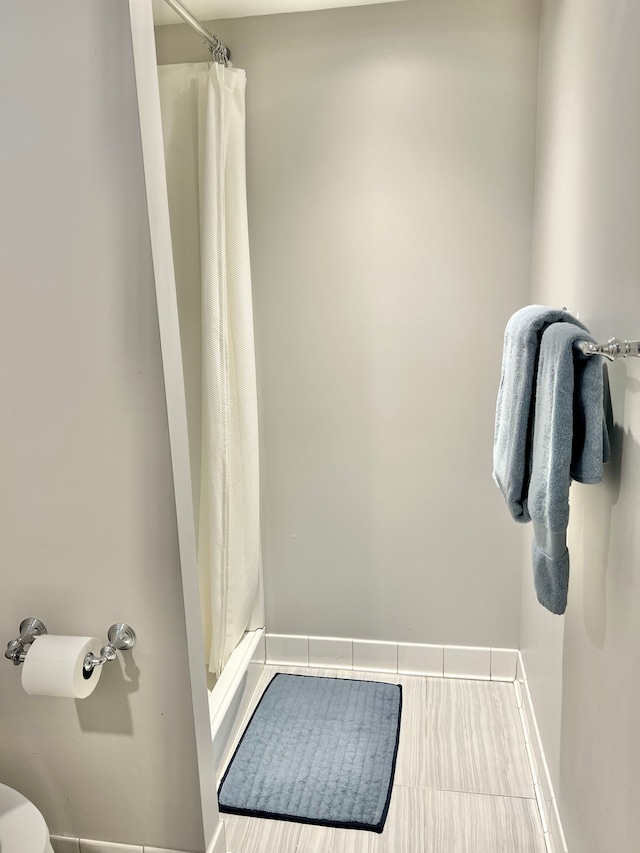 full bath with baseboards and curtained shower