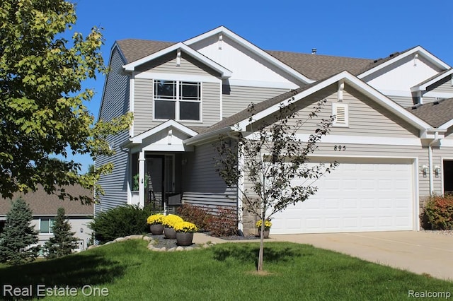 view of front of home with roof with shingles, a front yard, driveway, and a garage