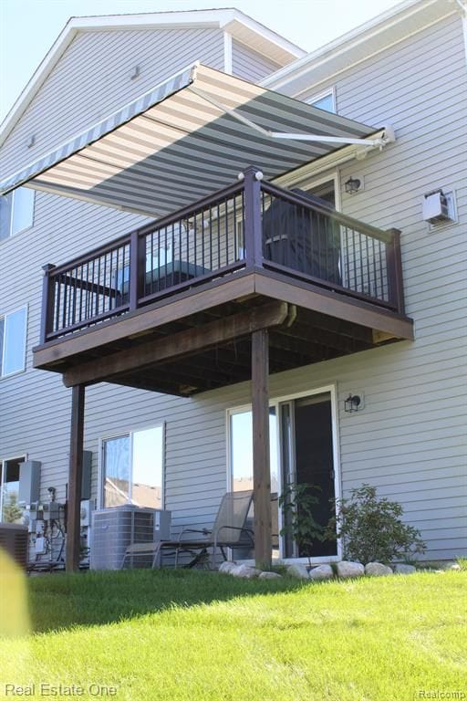 back of house featuring a lawn and a balcony