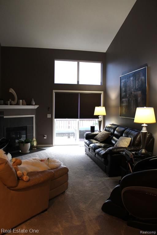 carpeted living area featuring high vaulted ceiling and a tile fireplace