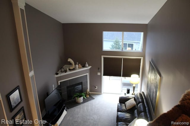 living room with carpet flooring, a high ceiling, a wealth of natural light, and a tile fireplace