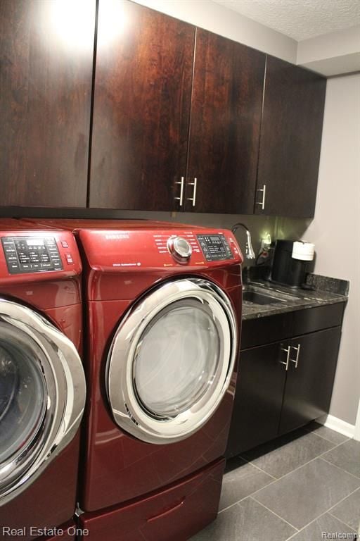 laundry area featuring tile patterned flooring, baseboards, separate washer and dryer, a sink, and cabinet space