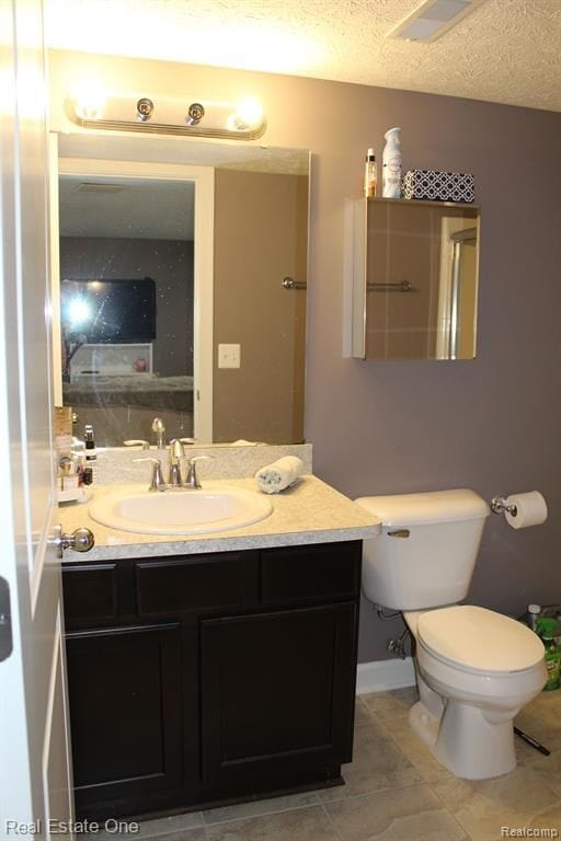 bathroom with a textured ceiling, visible vents, vanity, tile patterned floors, and toilet