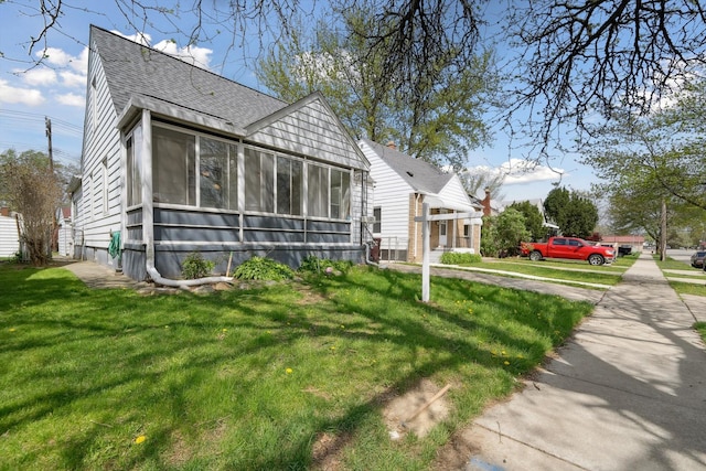 bungalow featuring a sunroom, a front lawn, and roof with shingles