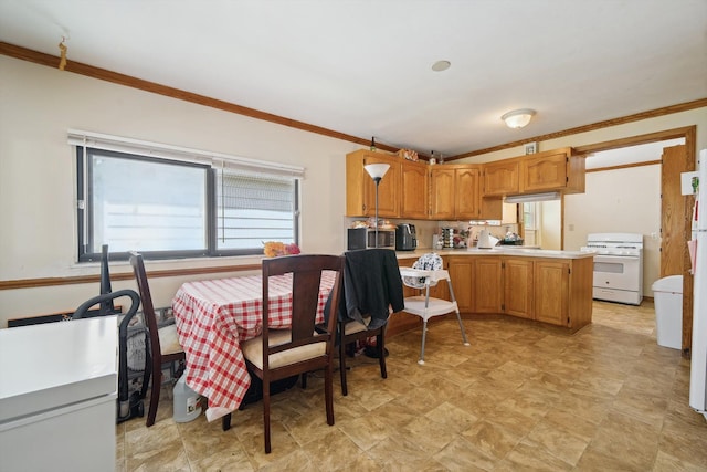 kitchen with ornamental molding, a peninsula, white gas stove, light countertops, and brown cabinets