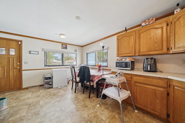 kitchen featuring baseboards, ornamental molding, brown cabinets, and light countertops