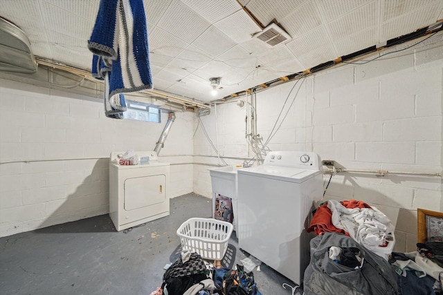 laundry area with washer and dryer, concrete block wall, laundry area, and visible vents