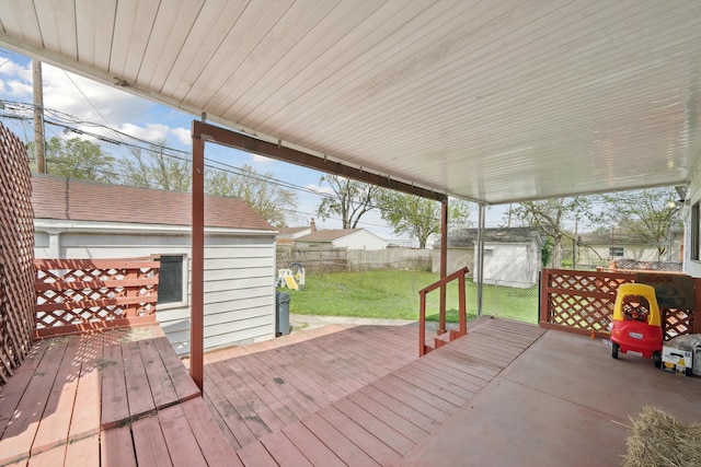 wooden terrace with a lawn, a fenced backyard, a shed, and an outbuilding