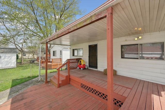 wooden terrace featuring a lawn and fence