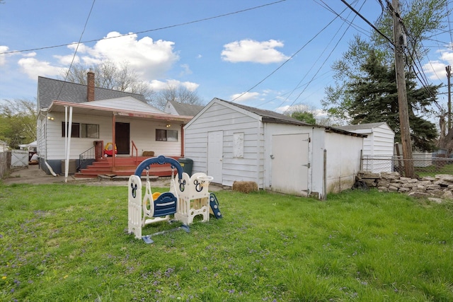 rear view of property with a shed, a yard, a chimney, and fence