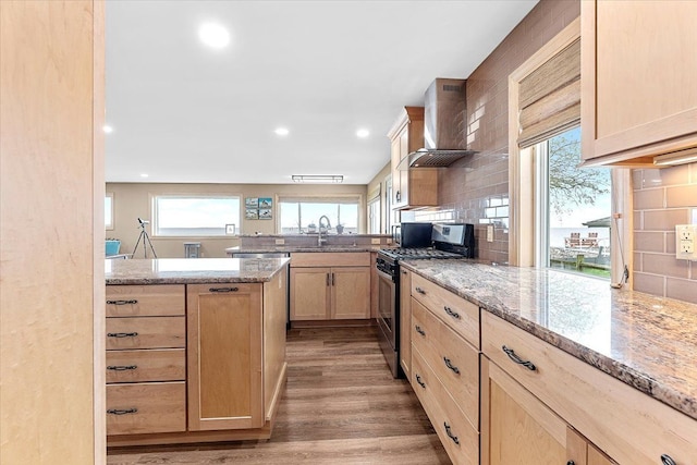 13516 Venetian Dr, Monroe, MI 48161 - kitchen with stainless steel gas range, light brown cabinetry, wall chimney range hood, a peninsula, and tasteful backsplash