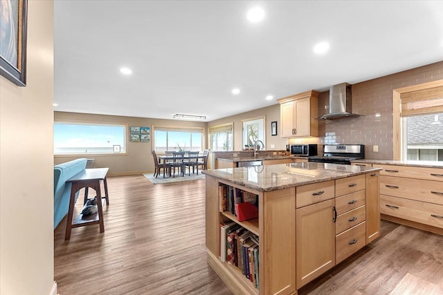 kitchen with appliances with stainless steel finishes, light brown cabinets, and wall chimney range hood
