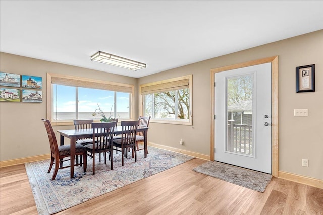 dining room featuring baseboards, plenty of natural light, and light wood-style flooring
