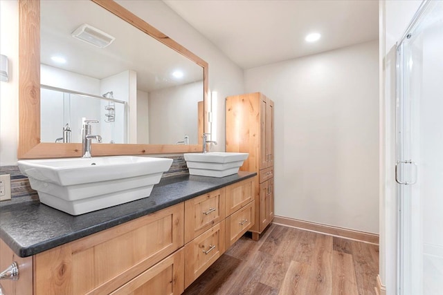 bathroom featuring recessed lighting, a shower stall, a sink, and wood finished floors