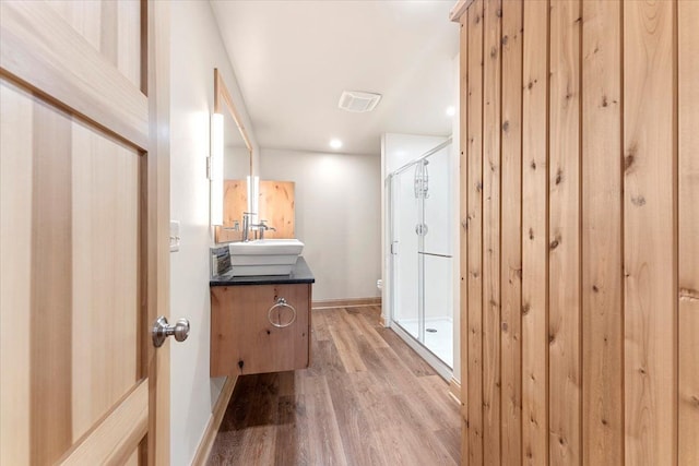 full bath featuring a shower stall, wood finished floors, vanity, baseboards, and toilet