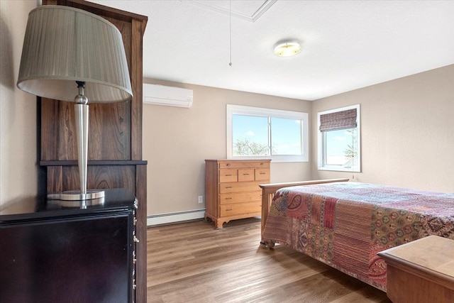 bedroom with a wall mounted air conditioner, wood finished floors, baseboard heating, and attic access