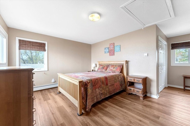 bedroom featuring baseboards, a baseboard heating unit, attic access, and light wood-type flooring