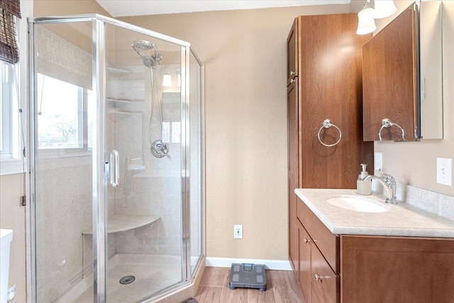 full bathroom with vanity, baseboards, a stall shower, and wood finished floors