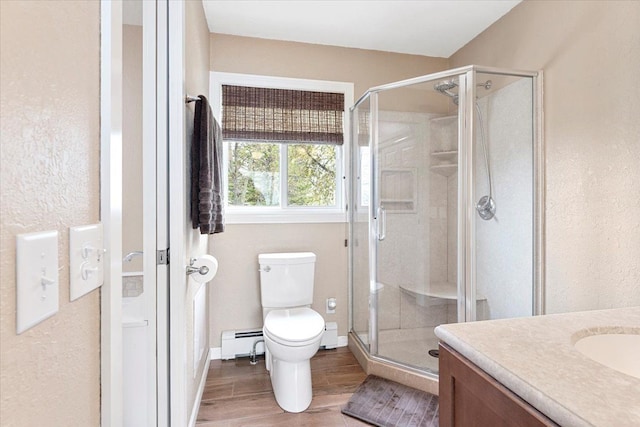 bathroom featuring a shower stall, a baseboard heating unit, toilet, and wood finished floors