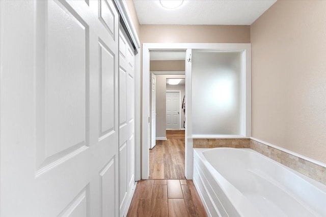 full bath with wood finished floors and a bath