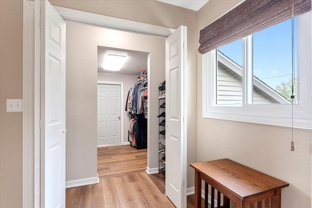 corridor featuring baseboards and light wood-type flooring