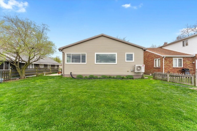 back of property with fence, ac unit, and a yard