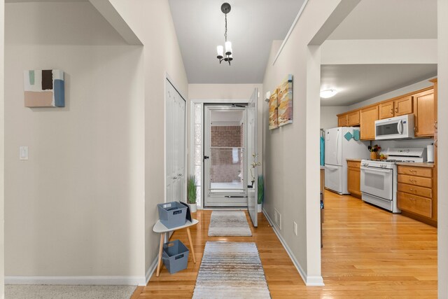 entrance foyer with visible vents, light wood-style flooring, baseboards, and a chandelier