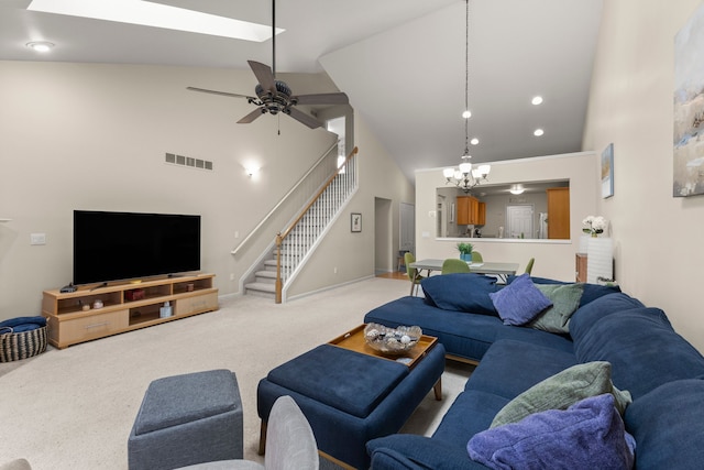 living room with light colored carpet, high vaulted ceiling, ceiling fan with notable chandelier, stairs, and visible vents