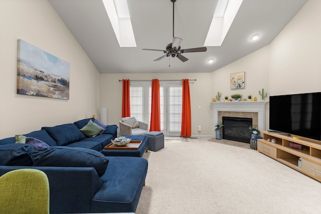 carpeted living room with vaulted ceiling with skylight, a ceiling fan, a tile fireplace, baseboards, and recessed lighting