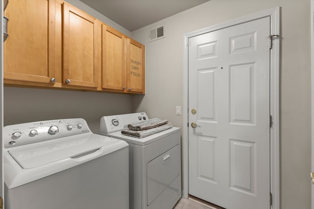 laundry area with visible vents, washer and clothes dryer, and cabinet space