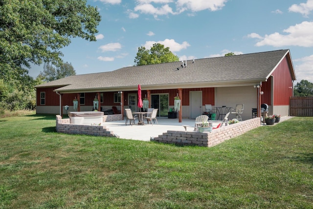 rear view of property with a lawn, a jacuzzi, a patio area, and roof with shingles