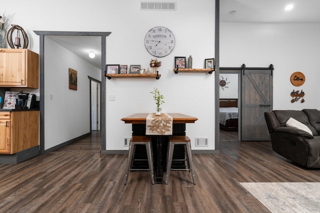 dining area with visible vents, a barn door, and dark wood-type flooring