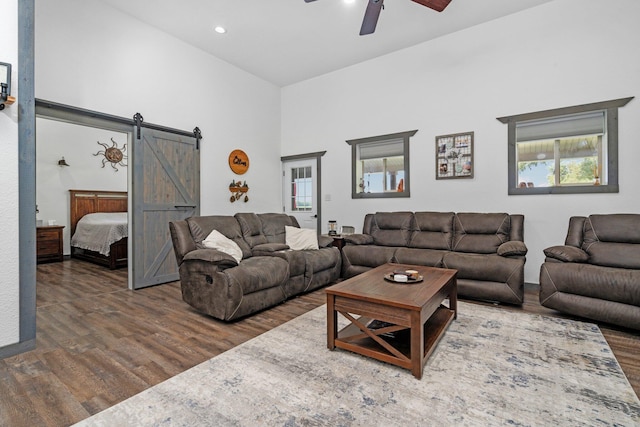 living room with a barn door, ceiling fan, wood finished floors, and a wealth of natural light