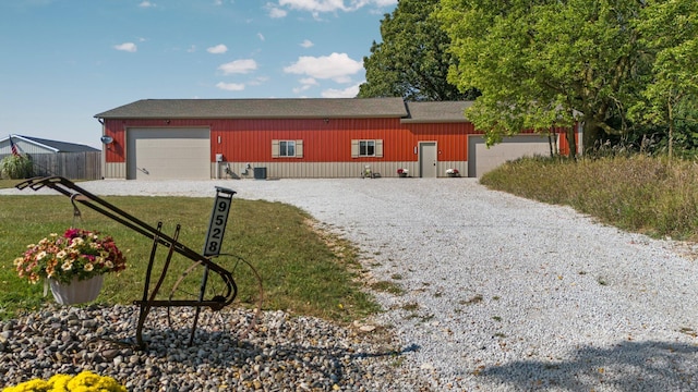 view of front of house with a garage, fence, a front yard, gravel driveway, and an outbuilding