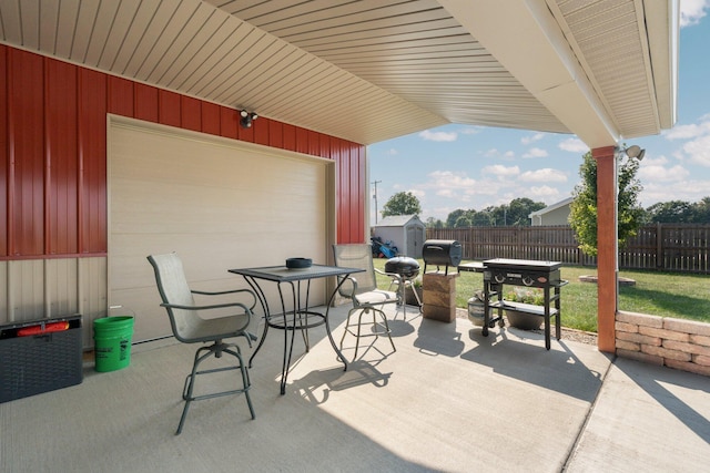view of patio with fence, a storage unit, an outdoor structure, and a garage