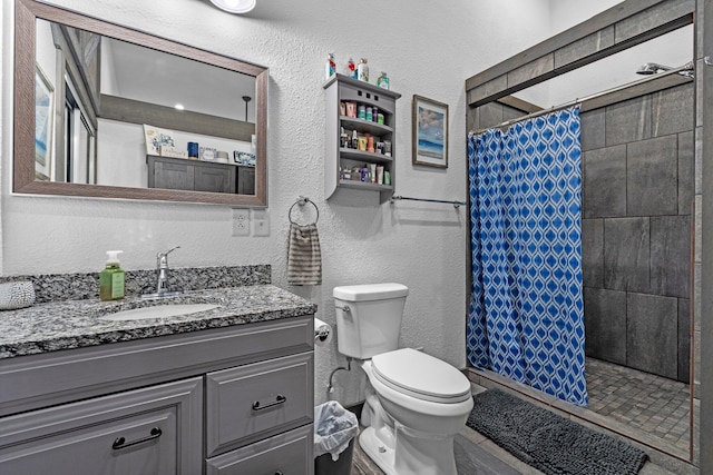 full bathroom with toilet, a textured wall, a shower stall, and vanity