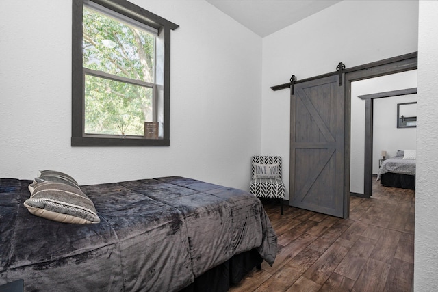 bedroom featuring dark wood-style flooring and a barn door