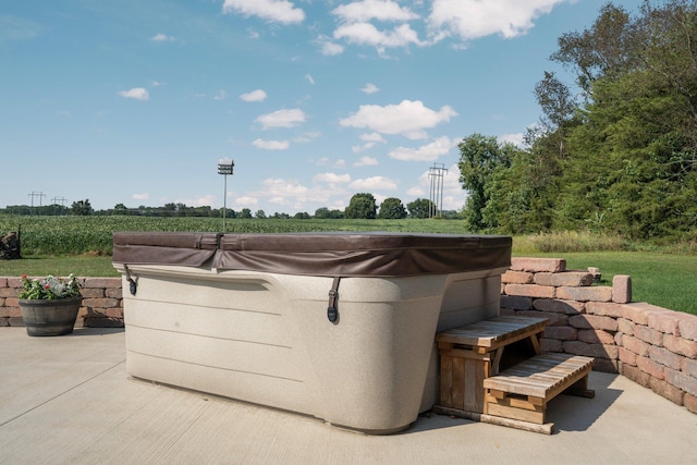 view of patio with a hot tub and a rural view