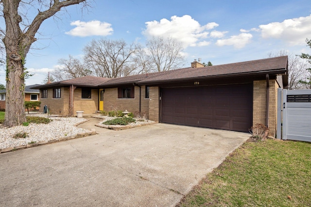 ranch-style home featuring brick siding, a garage, a chimney, and concrete driveway