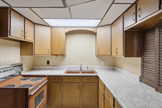 kitchen featuring electric stove, a sink, a drop ceiling, and light countertops