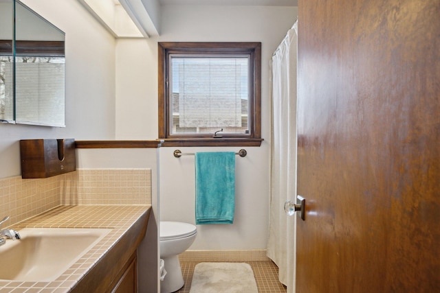 bathroom with toilet, tile patterned floors, decorative backsplash, and vanity