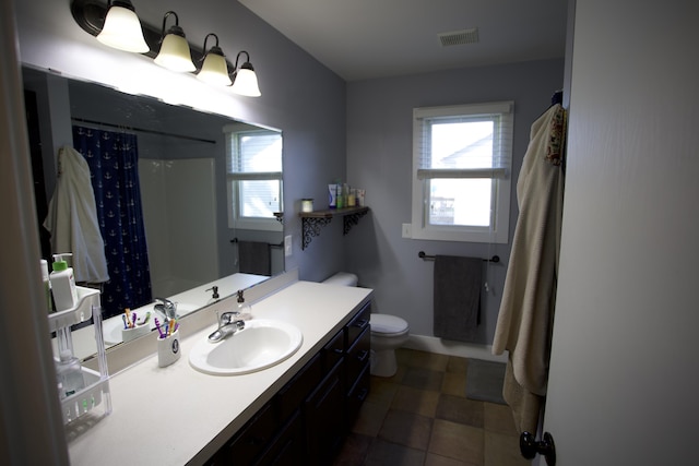 full bath featuring vanity, a shower with shower curtain, visible vents, and toilet