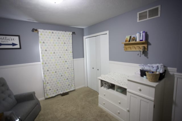 living area with carpet floors, visible vents, and wainscoting