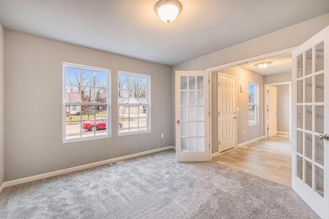 carpeted empty room featuring baseboards, a wealth of natural light, french doors, and visible vents