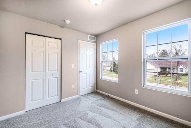 unfurnished bedroom featuring visible vents, carpet flooring, baseboards, and a closet
