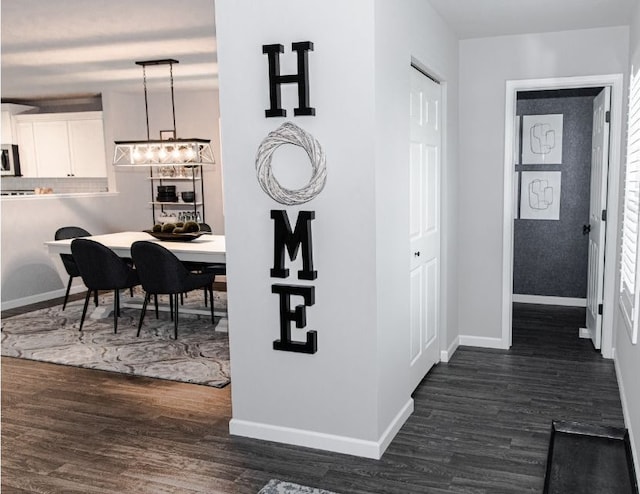 corridor featuring baseboards and dark wood-style flooring