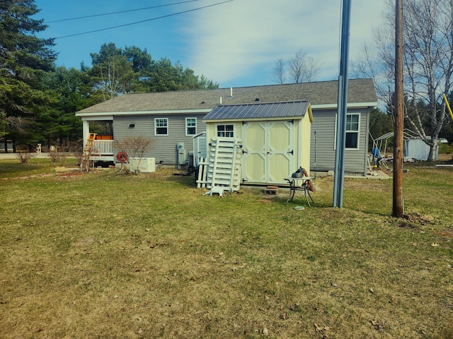 rear view of property with a lawn, a shed, and an outbuilding
